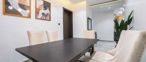 A modern dining area with a dark wooden table and cream-colored chairs.