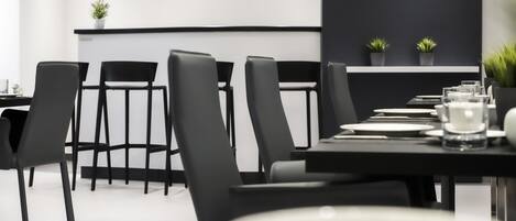 Un comedor moderno con sillas negras y una mesa larga dispuesta para una comida.