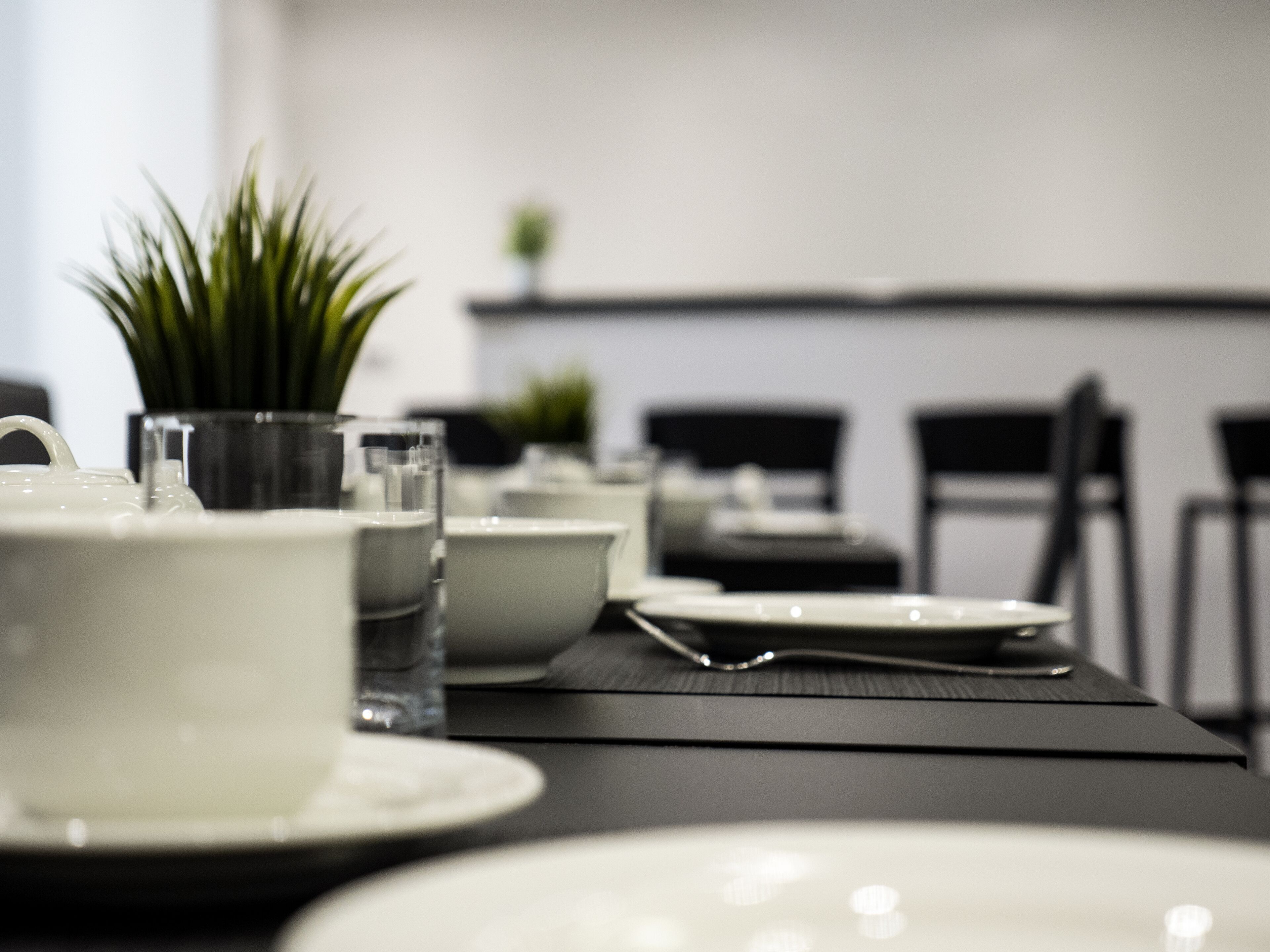 A dining table with white plates, a glass pitcher, and a small potted plant.