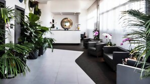 Un vestíbulo moderno con mostrador de recepción, zona de estar y ventanas amplias.