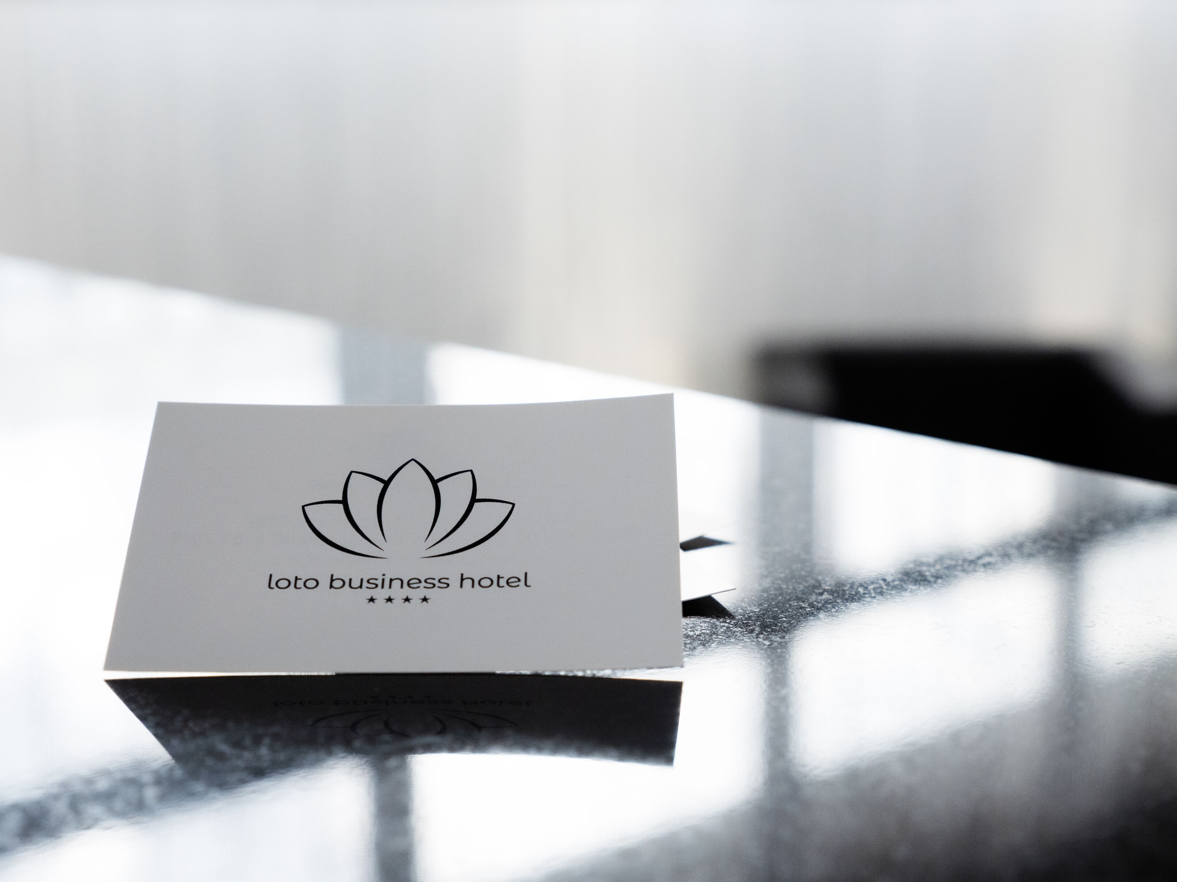 Une carte de visite pour un hôtel d’affaires, avec un logo représentant une fleur de lotus et le texte « Loto business hotel ».