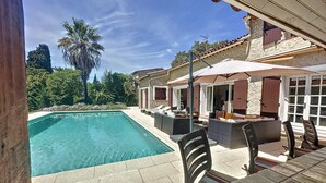 A swimming pool with lounge chairs and a covered patio area. - Spacious villa in town center, large swimming pool, Esterel view (Mandelieu-la-Napoule)