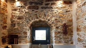 A kitchen with a stone wall, a window, a sink, a stove, and a kettle. - 1875 panoramic stone house (Filoti)