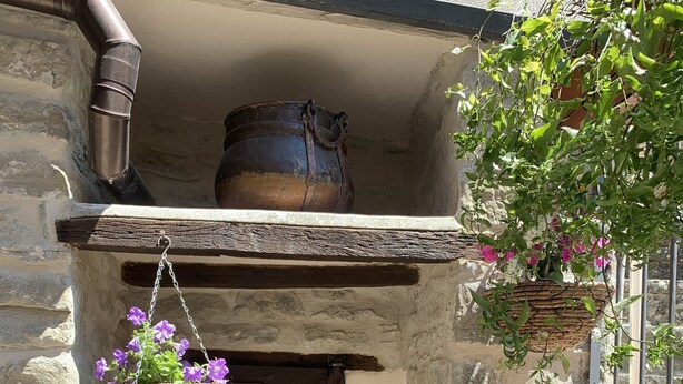 A rustic stone building with a wooden door, a hanging flower basket, and a stone ledge with a potted plant. - Vicar's Tower-Maghinardo living in history like a fairy tale.... (Palazzuolo Sul Senio)