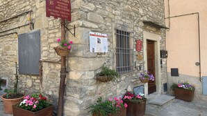 A stone building with a sign for a holiday home, outdoor flower pots, and a metal gate. - Vicar's Tower-Maghinardo living in history like a fairy tale.... (Palazzuolo Sul Senio)