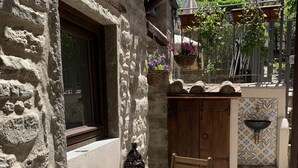 A rustic stone building with a wooden table and chairs, a hanging lantern, and a tiled sink area. - Vicar's Tower-Maghinardo living in history like a fairy tale.... (Palazzuolo Sul Senio)
