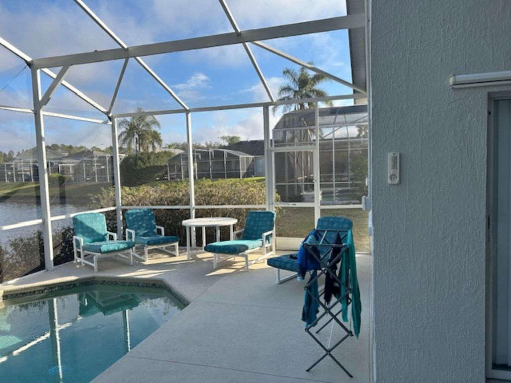 A covered outdoor area with a pool, chairs, and a table.