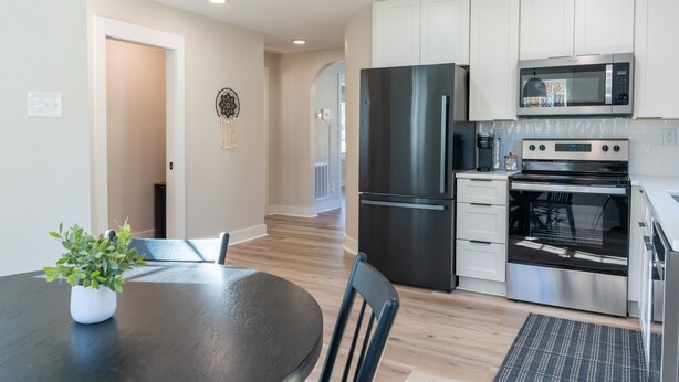 A modern kitchen with stainless steel appliances, a dining table with chairs, and a potted plant. - 2 BR King Bed Near Duke Hospital & Campus (Durham)