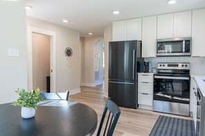 A modern kitchen with stainless steel appliances, a dining table with chairs, and a potted plant. - 2 BR King Bed Near Duke Hospital & Campus (Durham)
