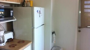 A kitchen with a microwave, toaster, refrigerator, and a trash bin. - Sea View One-Bedroom Apartment in St. Thomas

 (Charlotte Amalie West)