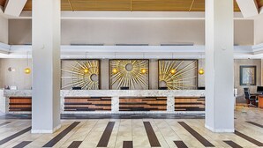 A reception area with a marble counter, three sunburst wall decorations, and a tiled floor. - 1BR Villa at Marriott Desert Springs Villas II - Great Value + Resort Amenities (Palm Desert)