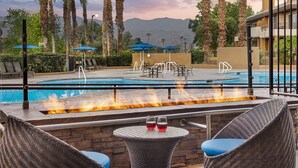 A poolside area with lounge chairs, a table with two glasses, and a fire feature. - 1BR Villa at Marriott Desert Springs Villas II - Great Value + Resort Amenities (Palm Desert)