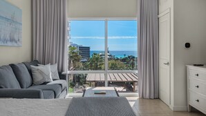 Habitación de hotel con un amplio ventanal que ofrece vistas al océano y a los edificios del complejo turístico.
