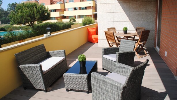 Un balcon agrémenté de meubles en osier, d’une petite table et d’une plante en pot.