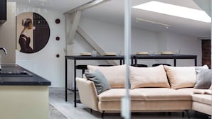 A modern interior with a sofa, dining table, and a wall-mounted artwork. - Blue Blood for 11 by Fragola Apartments (Kraków)