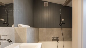 A modern bathroom with a bathtub, a shower, and a sink. - Blue Blood for 11 by Fragola Apartments (Kraków)
