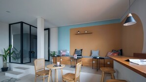 A modern, open-plan living area with a wooden dining table, chairs, and a bar area. - Cove Urbanier (Jakarta)