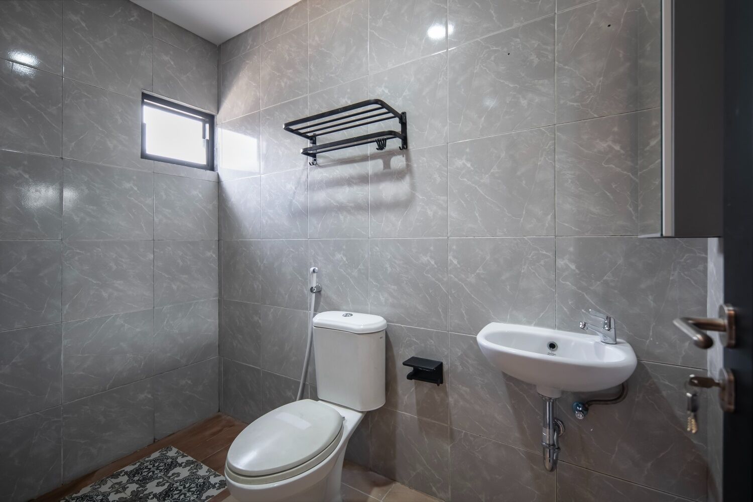 A modern bathroom with a toilet, bidet, and sink, all with marble tiles.