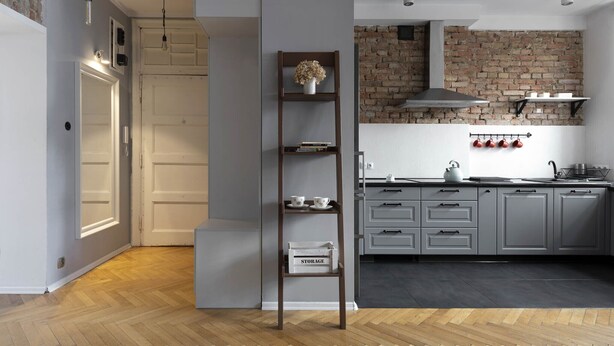 A modern kitchen with grey cabinets, a brick wall, and a wooden ladder shelf. - Roxy by Q4Apartments (Gdynia)