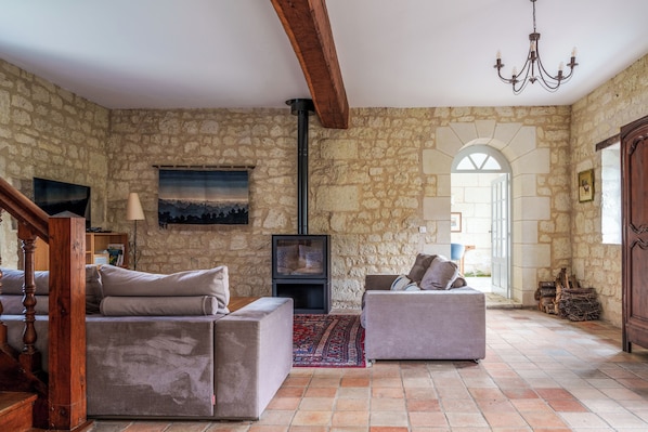 Ein Wohnzimmer mit Steinwänden, zwei Sofas, einem Kamin und einer Kristallleuchter.