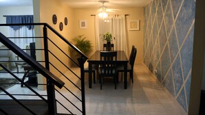 Un coin repas avec une table et des chaises, un ventilateur de plafond et une plante en pot.