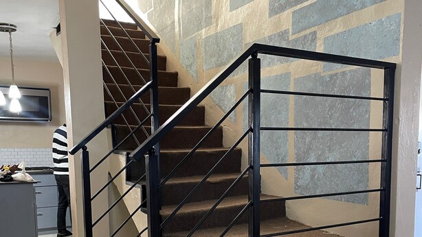 Un escalier avec des rampes noires et des murs de couleur beige.