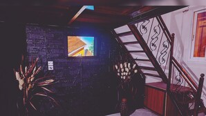 Una habitación con una escalera, un televisor en la pared y una planta.