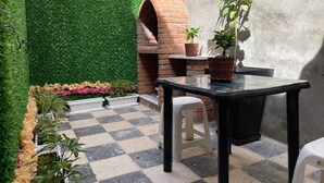 Un horno de ladrillo, suelo de cuadros y una mesa con un taburete.