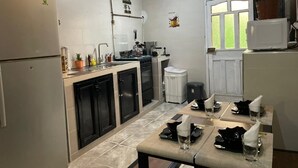 Cocina compacta con refrigerador, armarios y comedor con mesa dispuesta para dos.