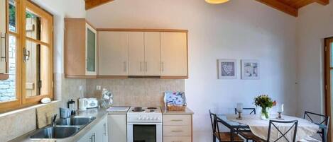 A kitchen with wooden cabinets, a stove, a sink, and a dining table with chairs.