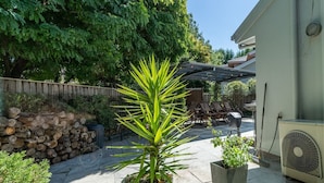 En terrasse med en stor plantekasse, et stabelt brænde og et overdækket siddeområde.