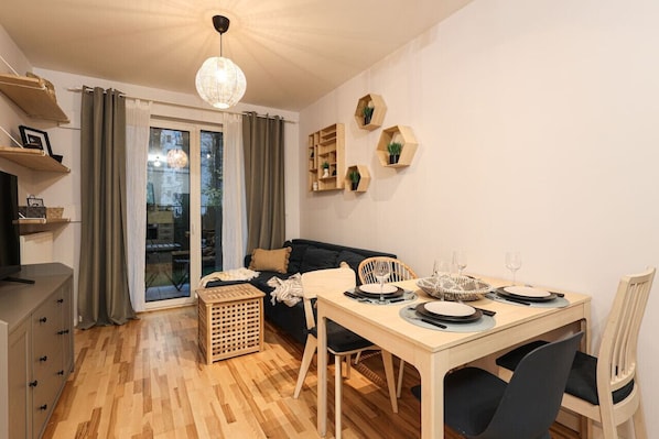 A dining area with a table set for two, a sofa, and a basket.