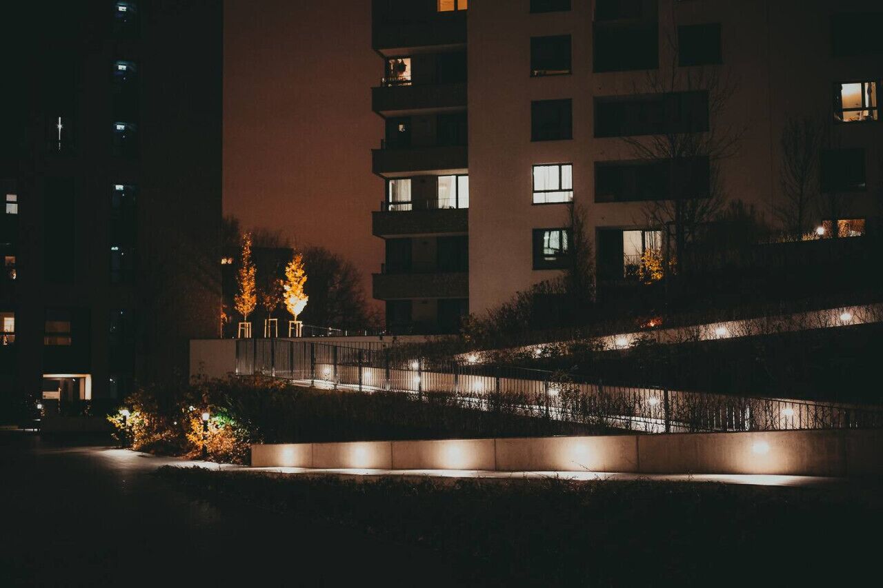 Ein Gebäude bei Nacht mit beleuchteten Fenstern und einem gut ausgeleuchteten Weg.