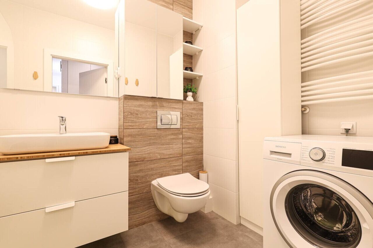 A modern bathroom with a sink, toilet, and washing machine.