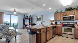 A modern kitchen with wooden cabinets, stainless steel appliances, and a dining area with a view. - Steps to Beach & Free Seasonal Beach Service (Miramar Beach)