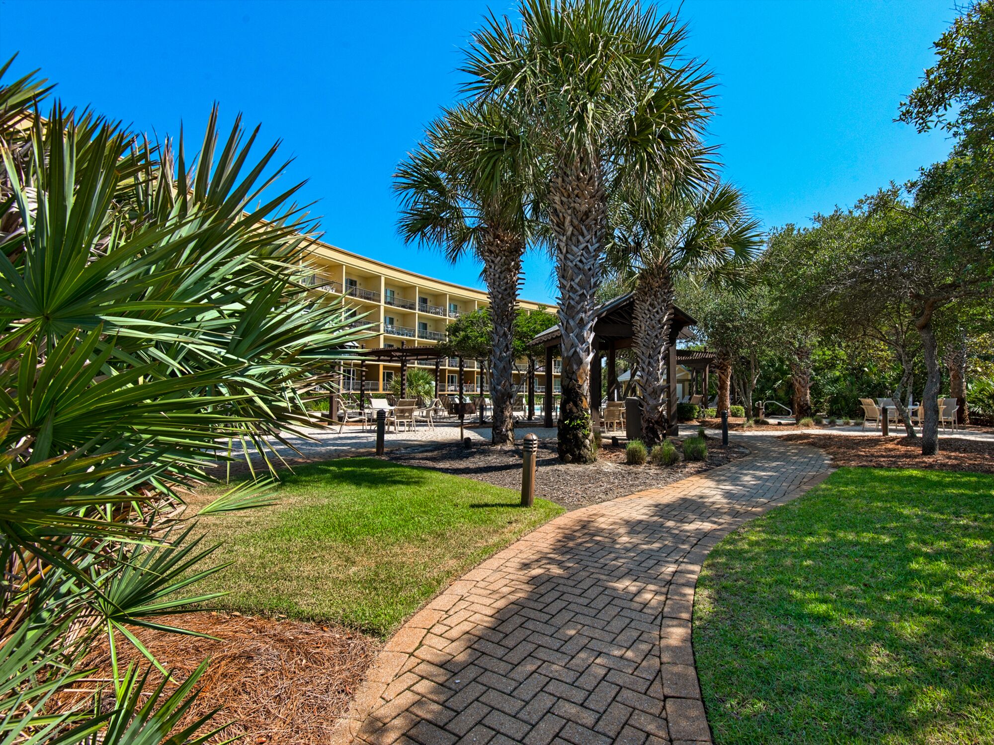 A paved pathway leading to a building with a yellow facade and multiple balconies.