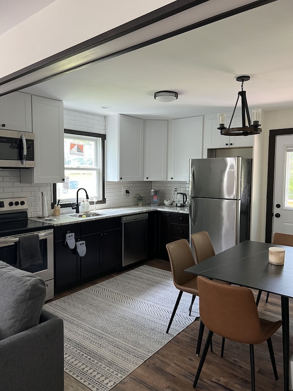 A modern kitchen with white cabinets, stainless steel appliances, and a dining area with a table and chairs.