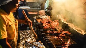 A person grilling meat on a barbecue.