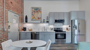 Una cocina moderna con armarios blancos, electrodomésticos de acero inoxidable y una mesa redonda con sillas.