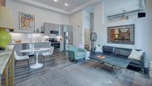 Una cocina moderna con armarios blancos, un comedor con mesa y sillas blancas, y una sala de estar con sofá y mesa de centro.
