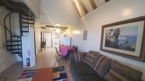 A living room with a sofa, a colorful rug, a staircase, and a dining area with chairs and a table. - Sea View 3 Bedroom Apartment in St. Thomas

 (St Thomas)