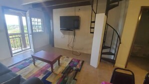 A living room with a sofa, a coffee table, a TV mounted on the wall, a staircase, and a balcony with a railing. - Sea View 3 Bedroom Apartment in St. Thomas

 (St Thomas)