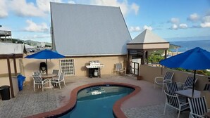 A swimming pool with a curved edge, surrounded by lounge chairs and umbrellas. - Sea View 3 Bedroom Apartment in St. Thomas

 (St Thomas)