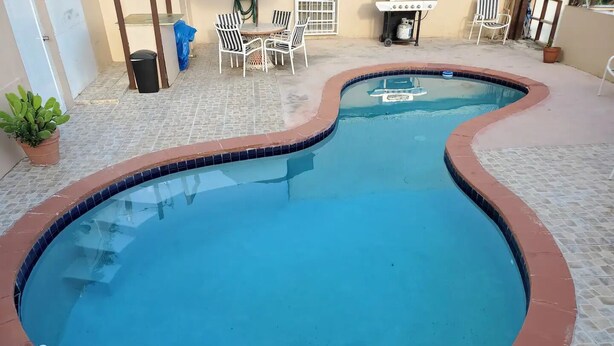 A swimming pool with a curved edge, surrounded by a tiled patio. - Sea View 3 Bedroom Apartment in St. Thomas

 (St Thomas)