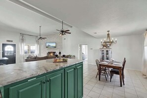 A spacious kitchen with a large island, dining area with a chandelier, and a fireplace. - Casa Blanca: Hot-Tub & Firepit w/Hill Country View (Fredericksburg)