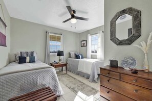 Un dormitorio con dos camas, ventilador de techo, cómoda y espejo.