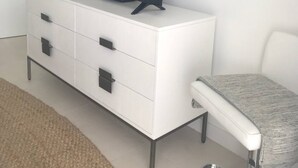 Una sala de estar moderna con un mueble blanco, un televisor de pantalla plana, un sofá blanco y una mesita.
