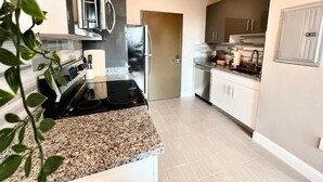 A modern kitchen with granite countertops, stainless steel appliances, and a view of the living area. - 503 Bohemian Romance Apartments in center city (Philadelphia)