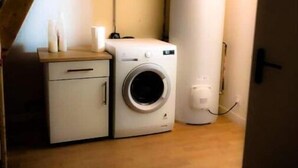 Uma lavanderia compacta com máquina de lavar e secadora, piso de madeira e teto inclinado.
