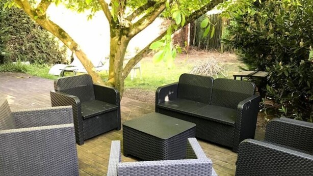 Uma área externa com mobiliário de vime e um deck de madeira.